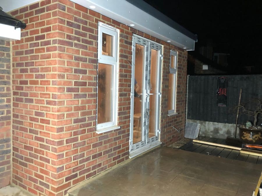 Brick modular extension with glazed doors photographed at dusk